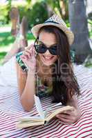 Smiling beautiful brunette lying and reading a book