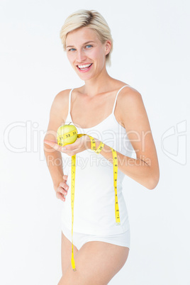 Happy woman holding an apple with hand on hip