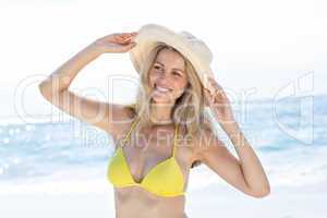 Smiling pretty blonde in bikini wearing straw hat