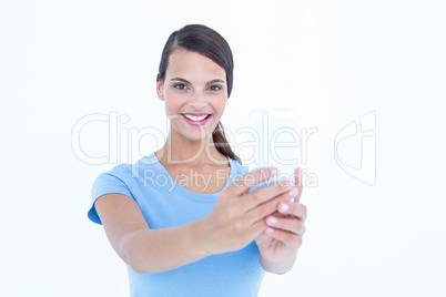 Pretty brunette using her smartphone looking at camera