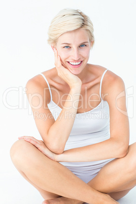 Happy woman sitting on the floor smiling at camera