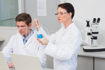 Scientists working with laptop and using a beaker