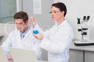 Scientists working with laptop and using a beaker