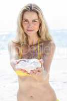 Smiling pretty blonde offering a seashell