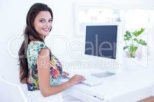 Smiling beautiful brunette using her computer