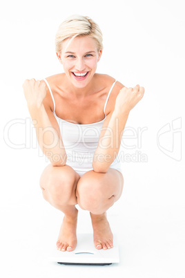 Happy attractive woman crouching on a scales