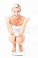 Happy attractive woman crouching on a scales