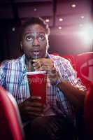 Young man watching a film and drinking soda