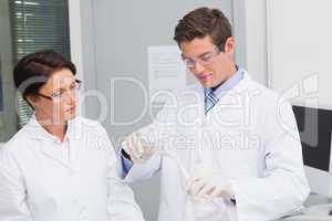 Scientists pouring chemical fluid in funnel