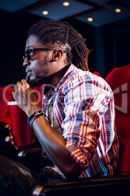 Young man watching a 3d film and drinking soda