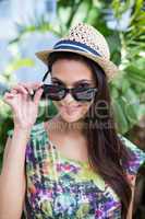 Smiling beautiful brunette wearing straw hat and sun glasses