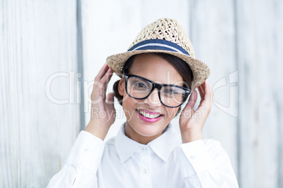 Pretty brunette looking at camera with hands on hat