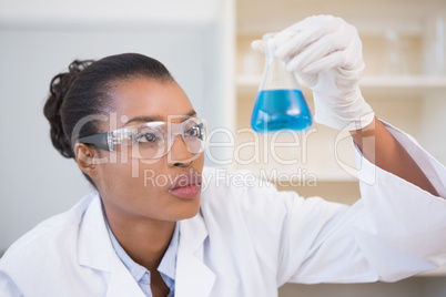 Scientist examining petri dish with blue fluid inside