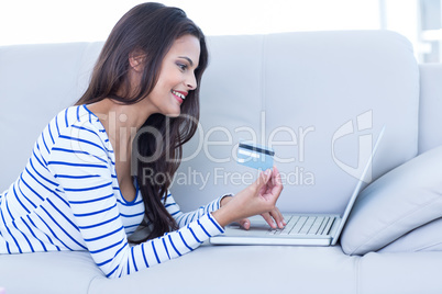 Smiling beautiful brunette doing online shopping on the couch