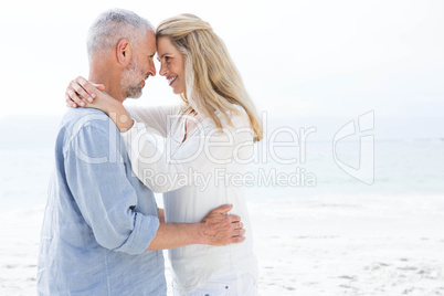 Happy couple smiling at each other by the sea