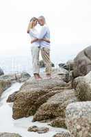 Happy couple standing on the rock and looking at each other