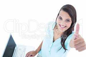 Pretty woman using her laptop with thumb up