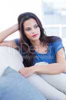 Thoughtful beautiful brunette sitting on the couch