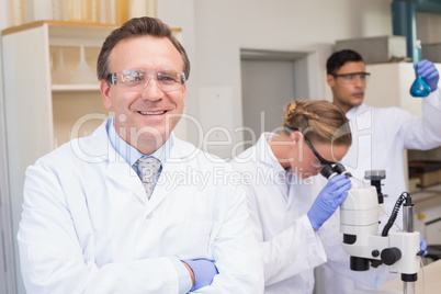 Smiling scientist looking at camera while colleagues working wit