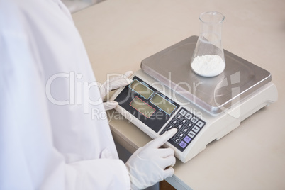 Scientist weighing beaker with white powder inside