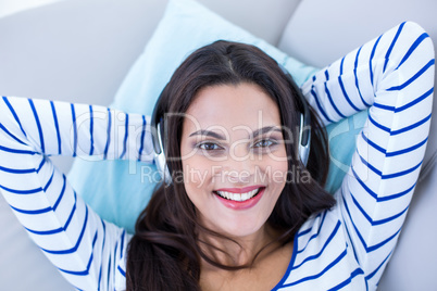 Smiling beautiful brunette relaxing on the couch and listening m Smiling beautiful brunette relaxing on the couch and listening m