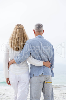 Happy couple hugging each other and looking at the sea Happy couple hugging each other and looking at the sea