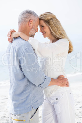 Happy couple smiling at each other by the sea