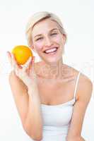 Happy woman holding an orange smiling at camera