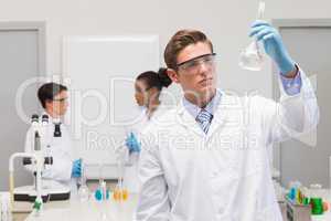Scientist looking at white precipitate while colleagues talking