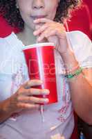 Young woman watching a film and drinking a soda