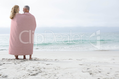 Happy couple hugging each other and looking at the sea with blan