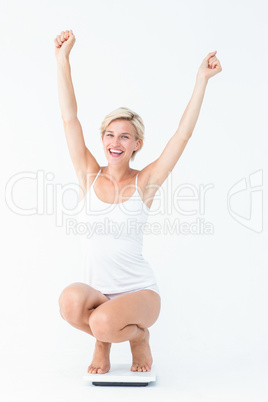 Happy attractive woman crouching on a scales