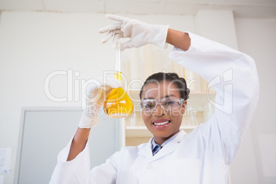 Scientist examining petri dish with orange fluid inside