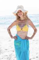 Smiling pretty blonde posing with sarong and straw hat