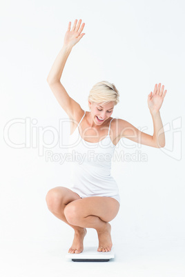 Happy attractive woman crouching on a scales