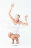 Happy attractive woman crouching on a scales