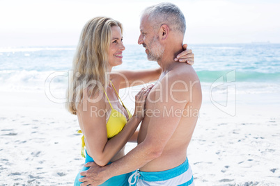 Happy couple standing by the sea and smiling at each other