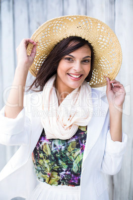 Smiling beautiful brunette wearing straw hat and looking at came