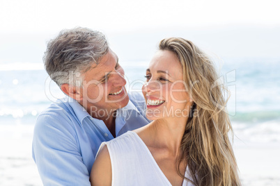 Happy couple smiling at each other by the sea