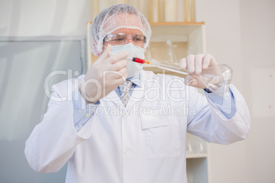 Scientist injecting red liquid in flask