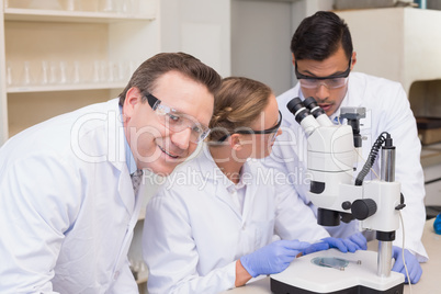 Concentrated scientists working together with microscope