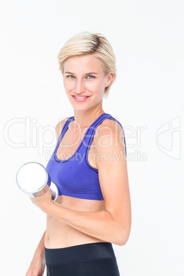 Happy woman in sportswear lifting dumbbell