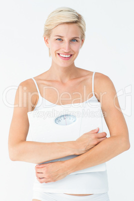 Smiling woman holding scales looking at camera