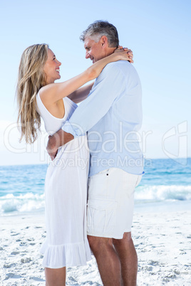 Happy couple standing by the sea and smiling at each other