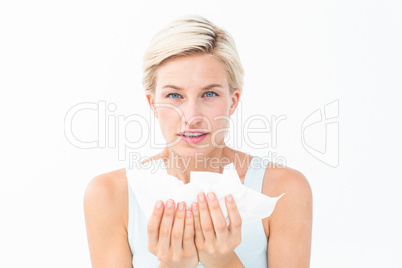 Sick woman holding tissues looking at camera