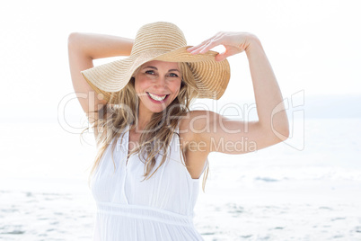 Smiling blonde in white dress looking at camera and wearing stra