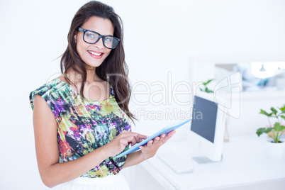 Smiling beautiful brunette standing in front of her computer