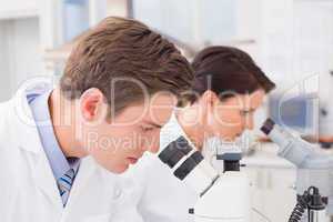 Scientists looking attentively in microscopes