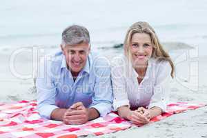 Happy couple lying on a blanket and smiling at camera