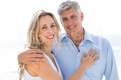 Happy couple standing by the sea and smiling at camera